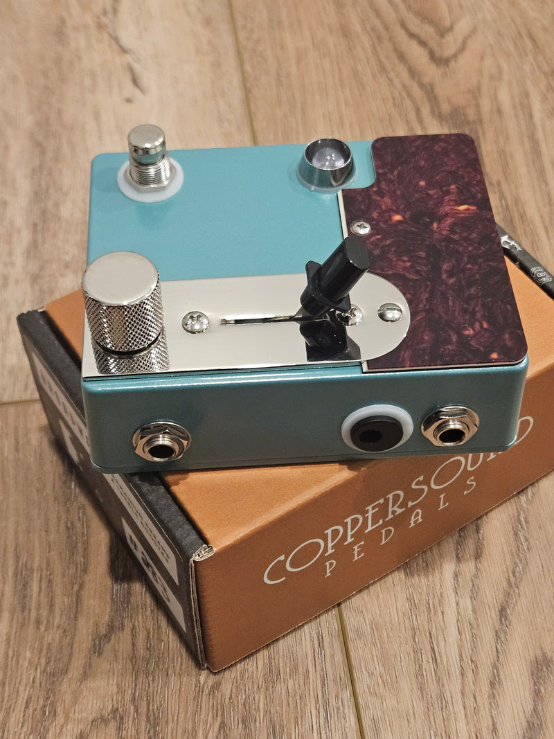 A CopperSound Broadway Treble Booster & Germanium Preamp Sherwood Green guitar pedal sitting on top of a box.