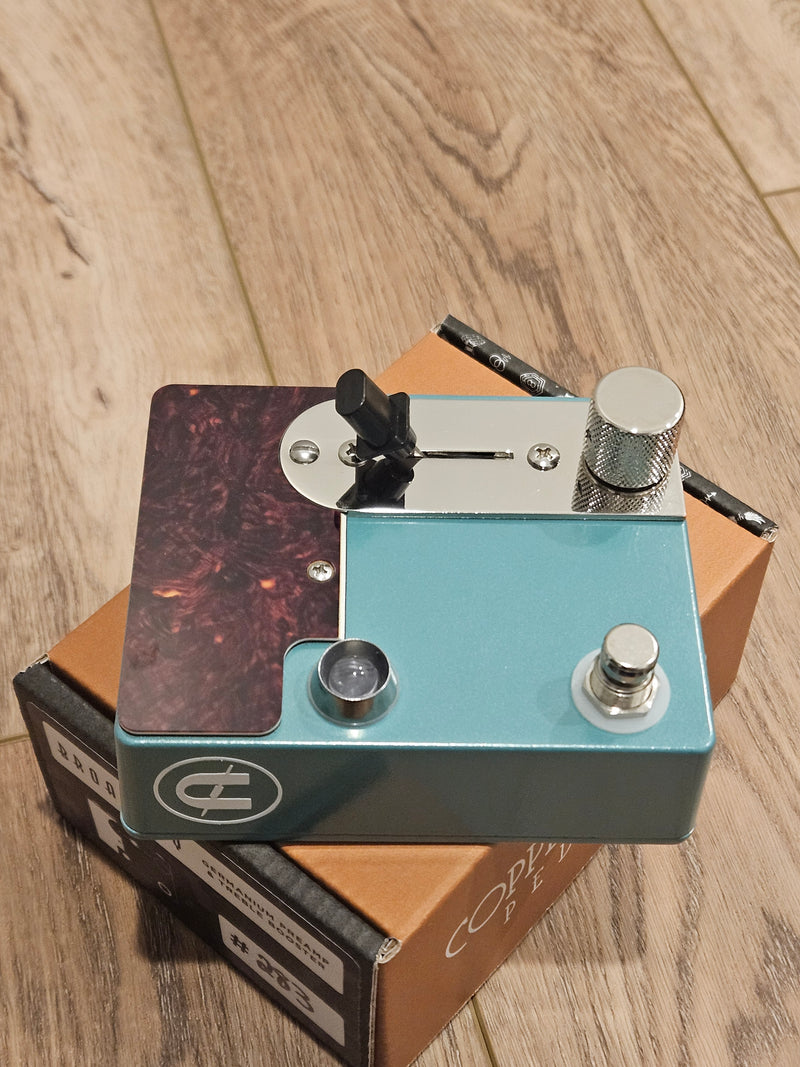 A CopperSound Broadway Treble Booster & Germanium Preamp Sherwood Green guitar pedal sitting on top of a box.
