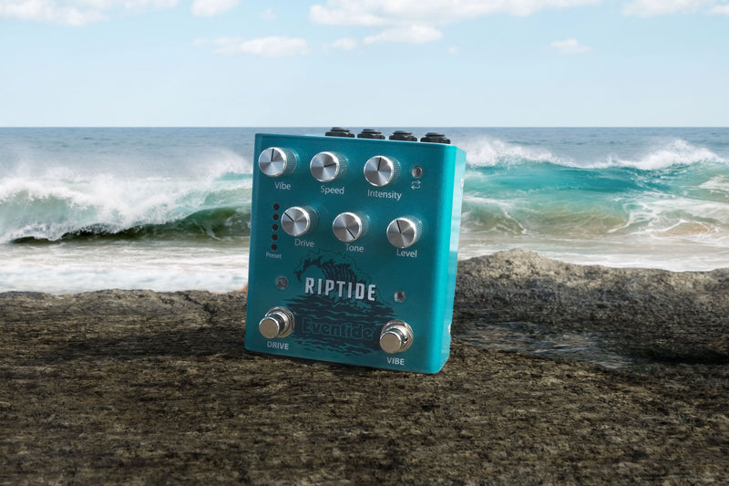 An Eventide Riptide Overdrive Uni-Vibe guitar pedal with presets sitting on a rock in front of the ocean.