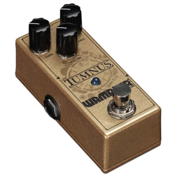 An important versatile addition to any guitar setup, the Wampler Tumnus Overdrive is a gold pedal with black knobs on it.