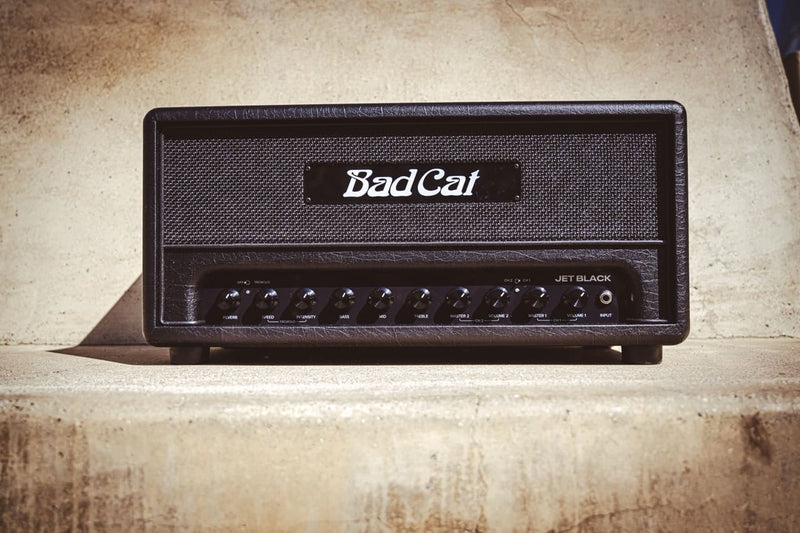 A Bad Cat Jet Black Head amplifier, known as an amp, sits on top of a concrete wall producing powerful sound and adjustable volume levels.